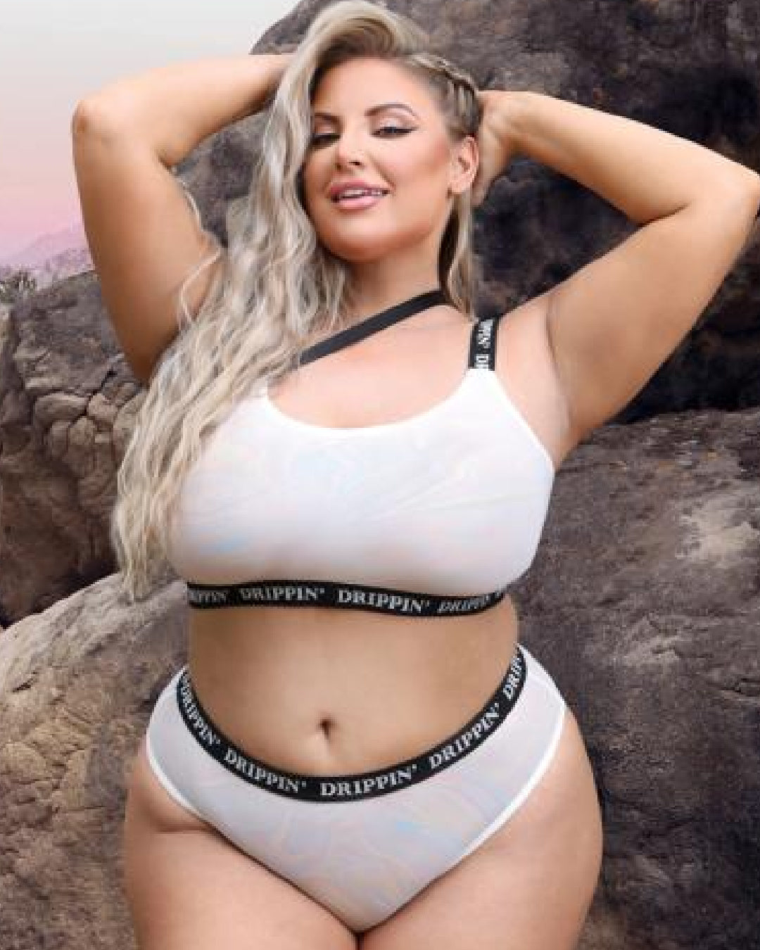 Blonde model standing in front of rocks wearing Drippin Strappy One-Shoulder Mesh Top & Cheeky Panty Queen