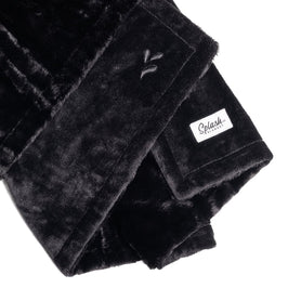 A close-up of the Splash Blanket Furlush Luxurious Faux Fur Waterproof Blanket - Small, showcasing its black plush, velvety texture, stitched "V" pattern, and a white "Splash" tag sewn on one end.
