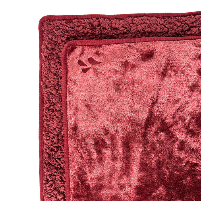 A close-up of the Splash Blanket The OG Waterproof Blanket - Large, a soft, reddish-burgundy pet blanket featuring a plush border and a small paw print cutout detail in the corner.