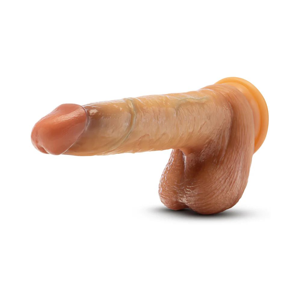 The DaVinci Ultra Realistic 8 Inch Silicone Dildo with Sliding Foreskin in Caramel, by Blush, is a highly detailed prosthetic penis. Made from liquid silicone, it features realistic skin texture and coloring with a meticulously designed shaft, glans, and scrotum to closely mimic the appearance of a natural penis. The product is displayed on a plain white background.