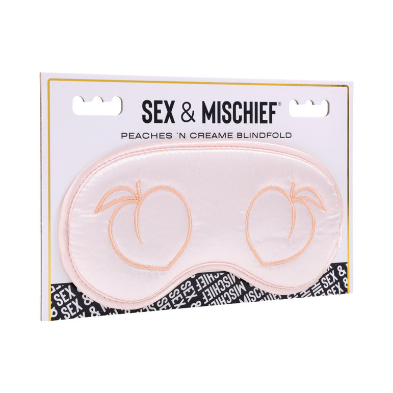 The Peaches 'n Cream Silky Blindfold by Sportsheets is a luxurious intimate accessory crafted from pink satin, adorned with charming peach embroidery. Its packaging features a distinctive black and white pattern along the bottom edge.